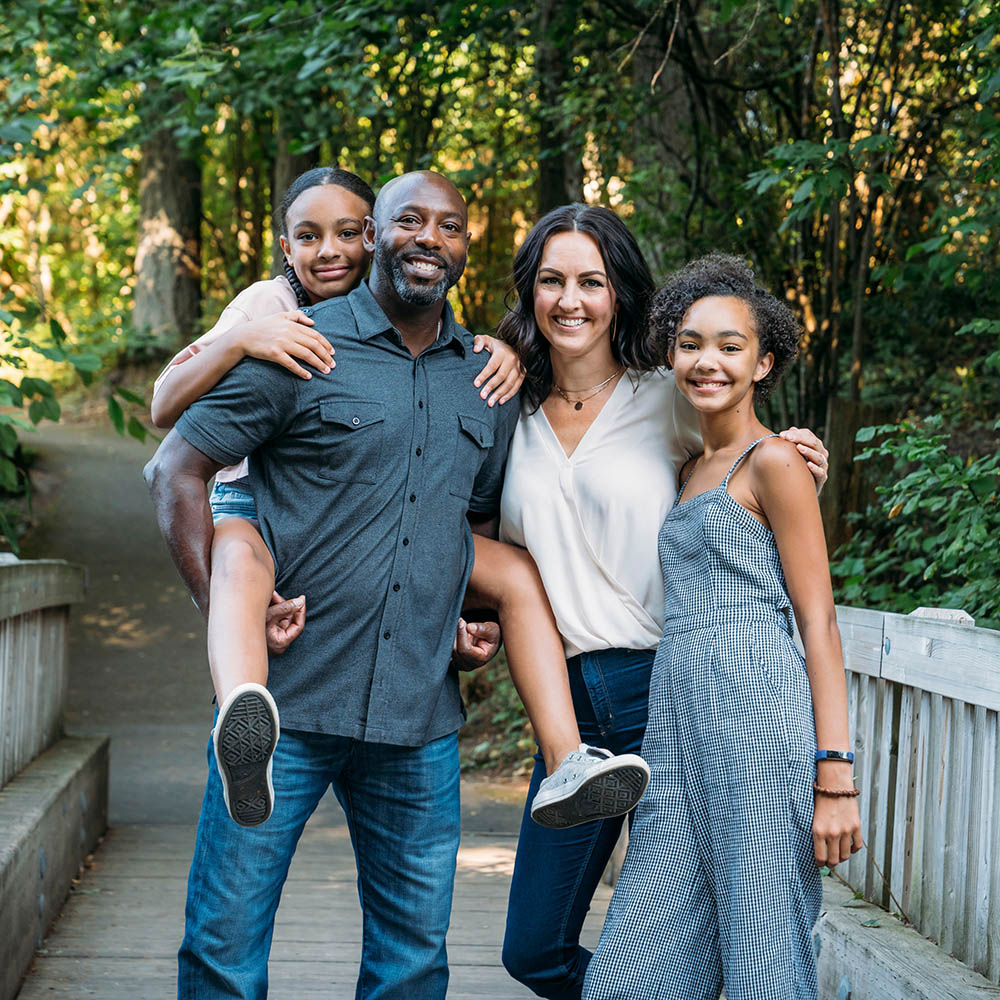 Portrait of happy mixed race family on bridge in nature park